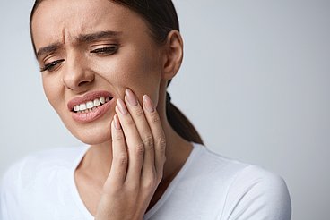 Eine Frau hat Zahnschmerzen Hier sieht man eine Frau die sich die Wange hält, weil sie Zahnschmerzen hat. Sie hat Probleme mit den Zähnen. © puhhha / adobe stock