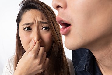 Frau hält sich die Nase zu. Eine Frau hält sich die Nase zu, weil ein Mann Mundgeruch hat. © kei907 / adobe stock
